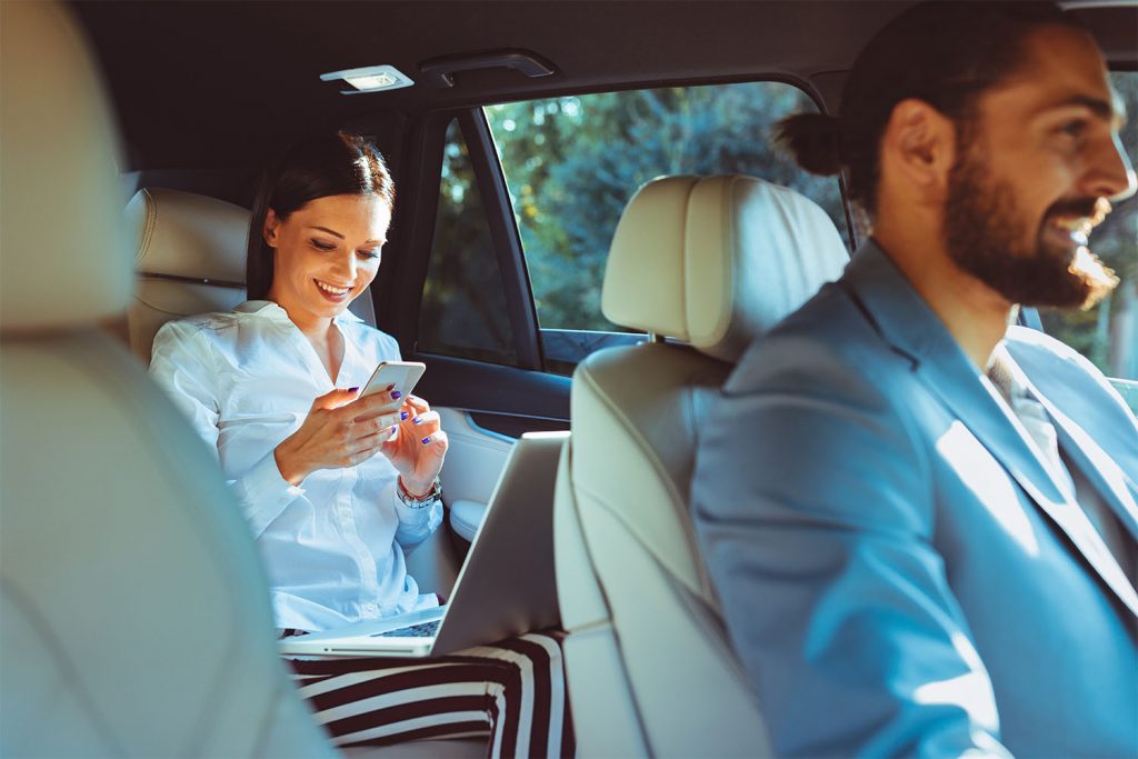 Frau mit Smartphone wird in einem SUV gefahren