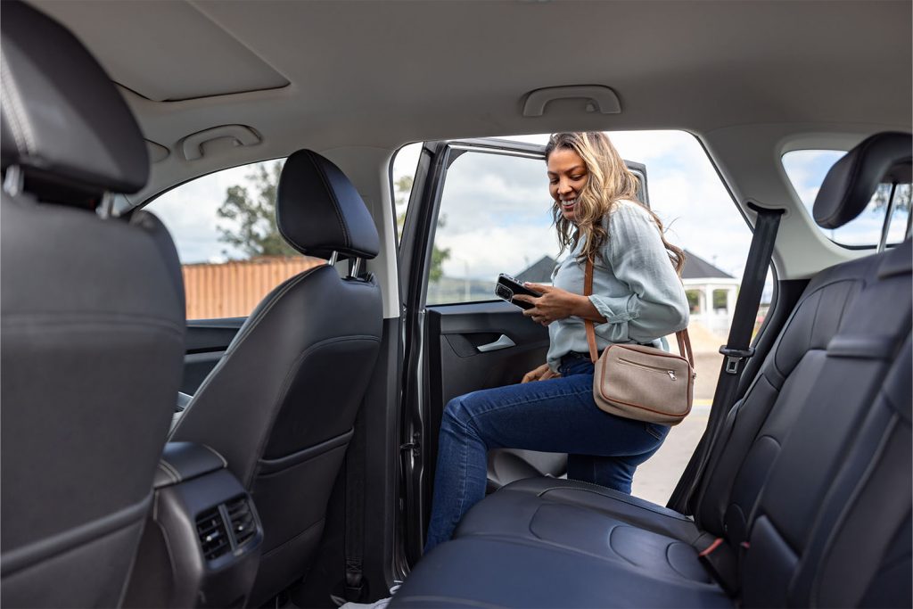 Frau steigt hinten in ein Auto ein